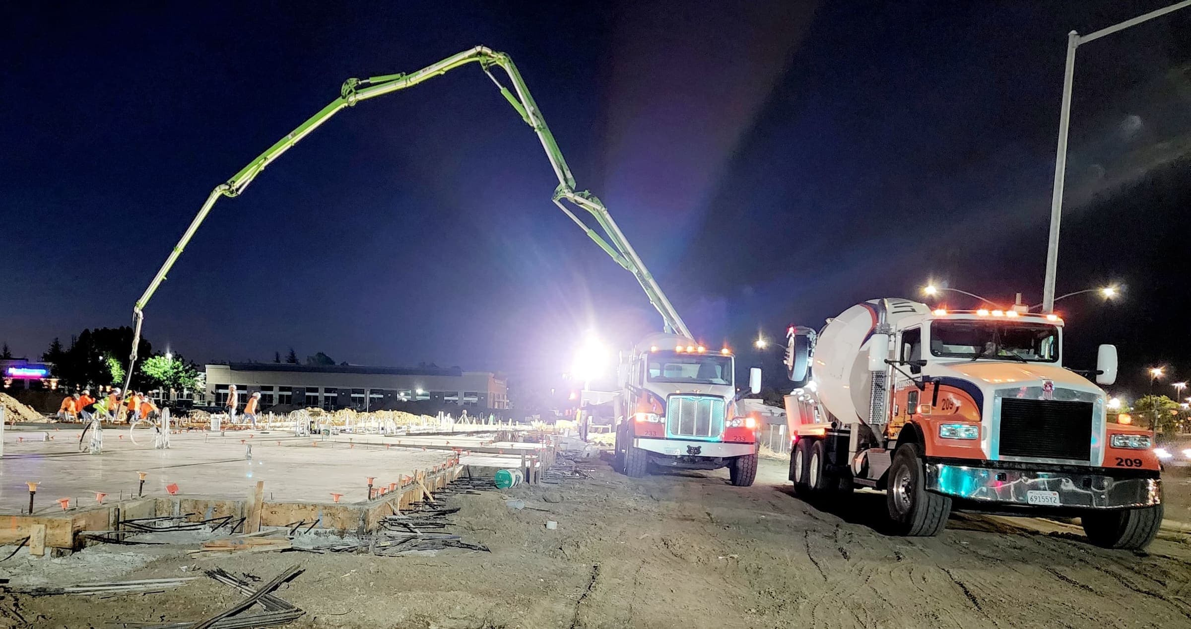 Two Livingston's mixer trucks feeding a boom pump during a night commercial slab pour